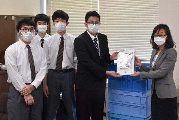 伊東昭代教育長(右)にフェースシールドが入った袋を手渡す県立聴覚支援学校の生徒たち=宮城県庁で