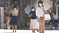 猛暑日の中、日傘を差して歩く人たち。コロナ禍からの経済復興には温暖化防止の政策も求められている＝福岡県久留米市で2020年6月8日、徳野仁子撮影