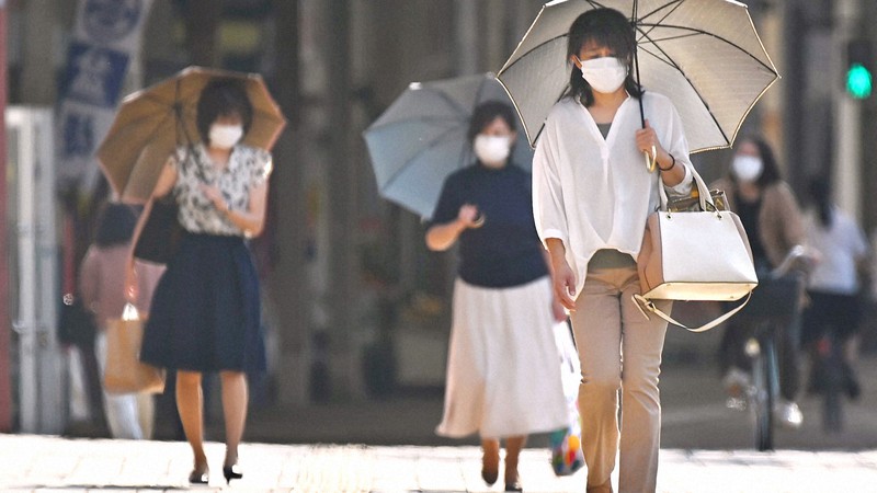 猛暑日の中、日傘を差して歩く人たち。コロナ禍からの経済復興には温暖化防止の政策も求められている=福岡県久留米市で2020年6月8日、徳野仁子撮影