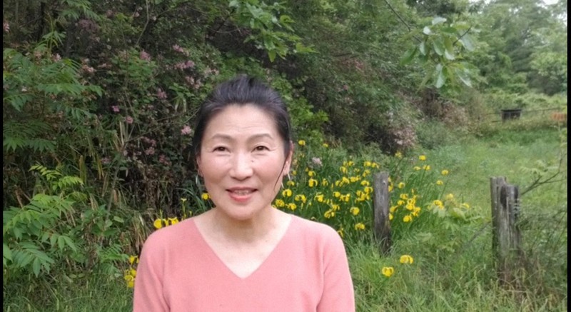 緑の木々の中で詩を朗読するフリーアナウンサーの水野晶子さん=ユーチューブから