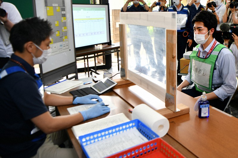避難者役の熊本市職員(右)をアクリル板越しに問診する避難所運営訓練の様子=熊本市南区の南部公民館で2020年6月8日午後3時35分、清水晃平撮影