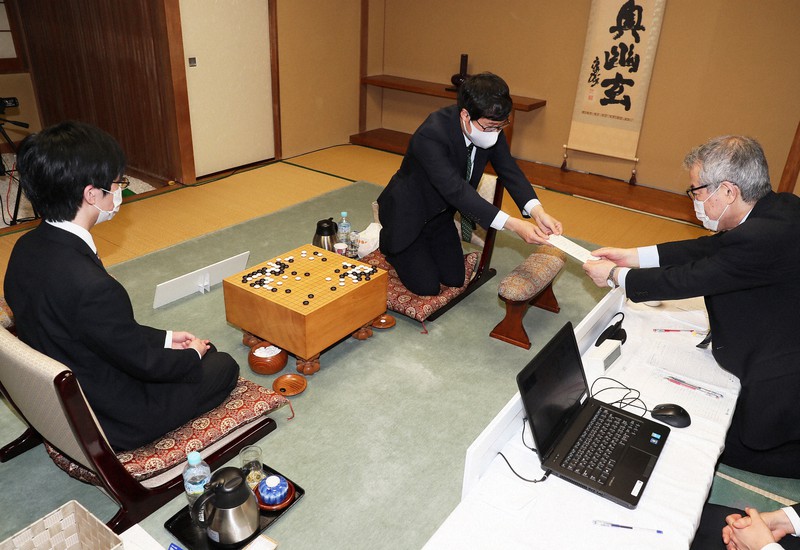 立会の二十四世本因坊秀芳(石田芳夫九段)に封じ手を渡す本因坊文裕(中央)。左は挑戦者の芝野虎丸名人=東京都千代田区の日本棋院で2020年6月13日午後5時2分、玉城達郎撮影