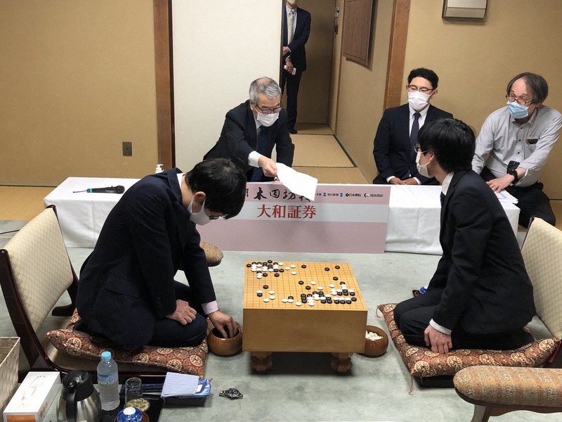 本因坊文裕(手前左)の封じ手を挑戦者の芝野虎丸名人(同右)に示す立会の二十四世本因坊秀芳=東京都千代田区の日本棋院で2020年6月14日午前9時5分、新土居仁昌撮影