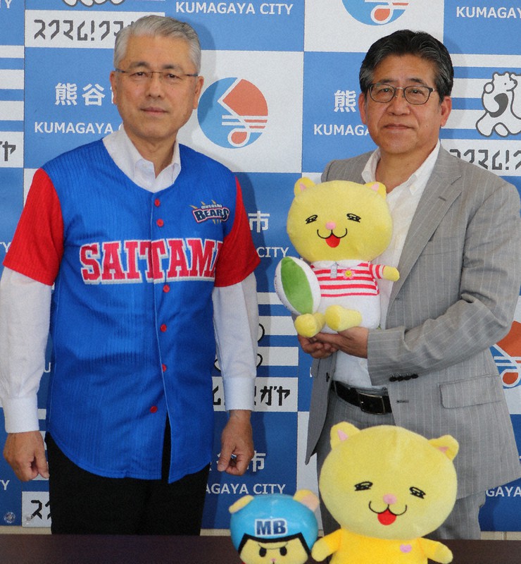 協定締結後、埼玉武蔵ヒートベアーズのユニホームを着た富岡清市長(左)と今井英雄球団代表=埼玉県熊谷市役所で