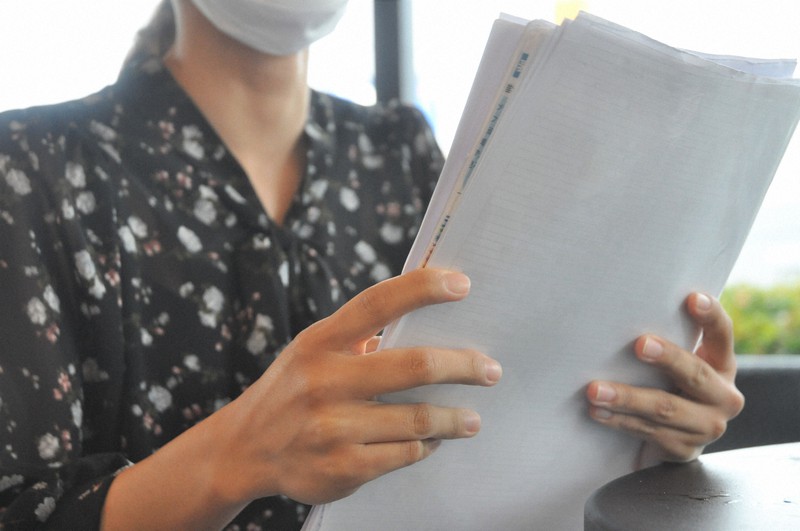 学生支援緊急給付金に関する資料などを見つめる看護専門学校3年の女性=宮崎市内で、杣谷健太撮影
