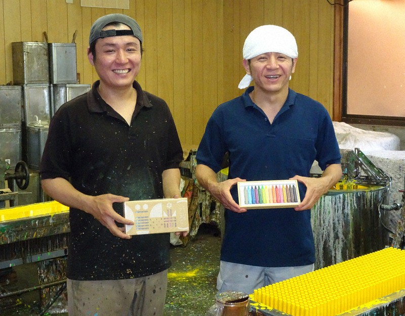 クレヨン工房で、蜜ろうから作った「とういちクレヨン」を手にする水谷正幸社長(右)と弟の水谷和幸工場長=名古屋市南区の東一文具工業所で