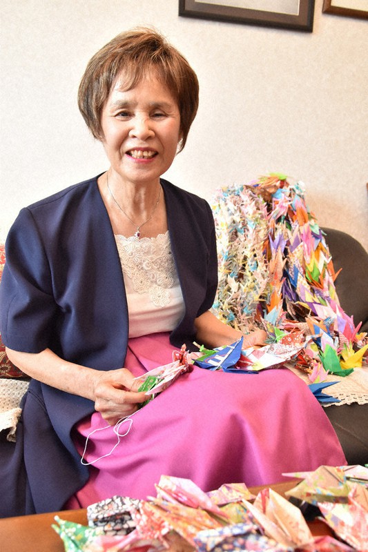 折り鶴に糸を通す空民子さん。ピンクのスカートはお気に入りの1着だ=広島市中区江波南2で、小山美砂撮影