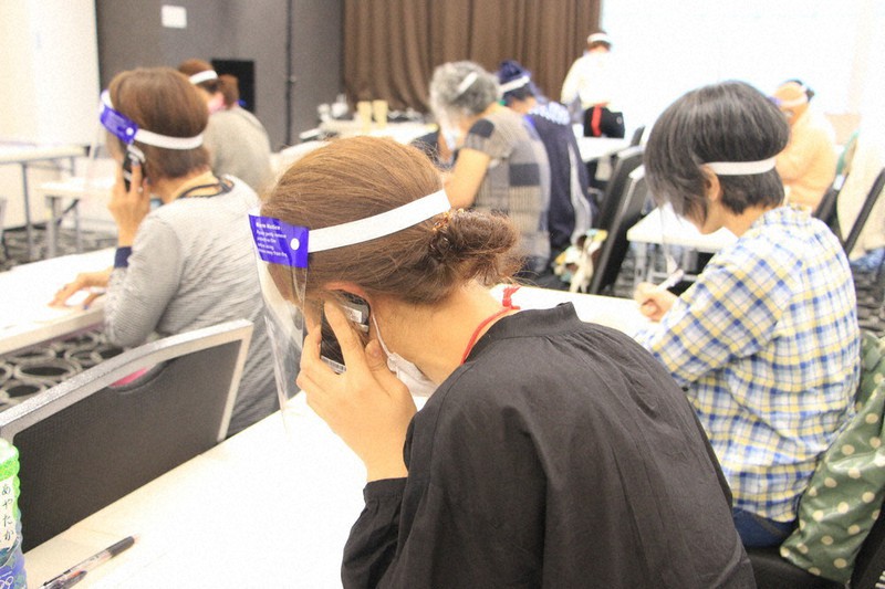 フェースシールドとマスクを着用して支援を求める電話をかけるスタッフら=東京都新宿区で19日、稲垣衆史撮影