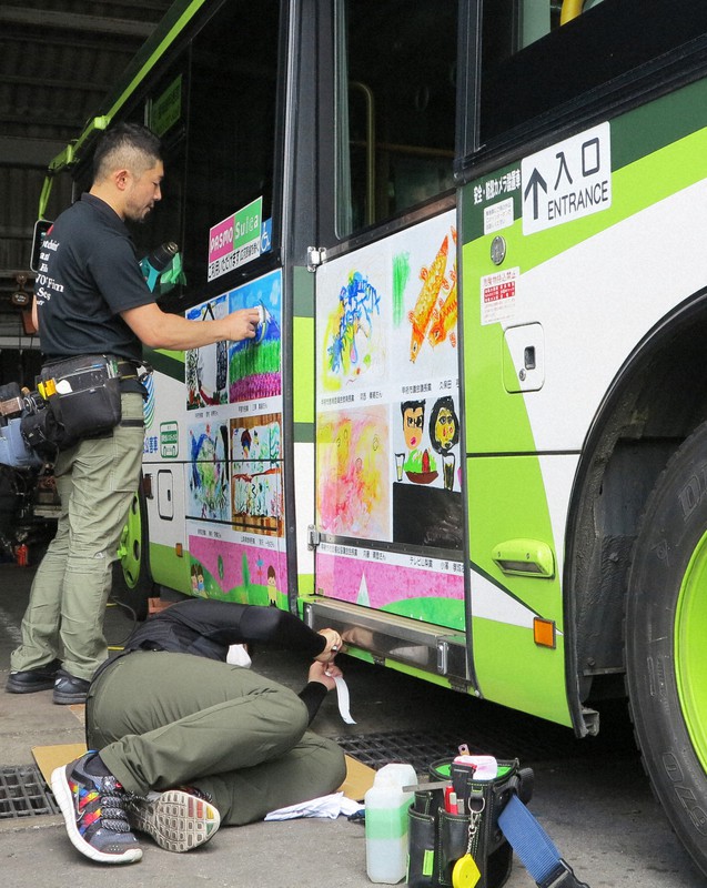 入賞作品を写したシートをバスの車体に貼る甲府青年会議所のメンバー=山梨県甲斐市内で2020年6月21日、山本悟撮影