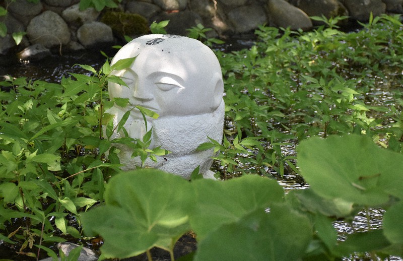 庭園の小川にひっそりとたたずむ石像。どこか涼しげだ=山形県上山市のリナワールドで