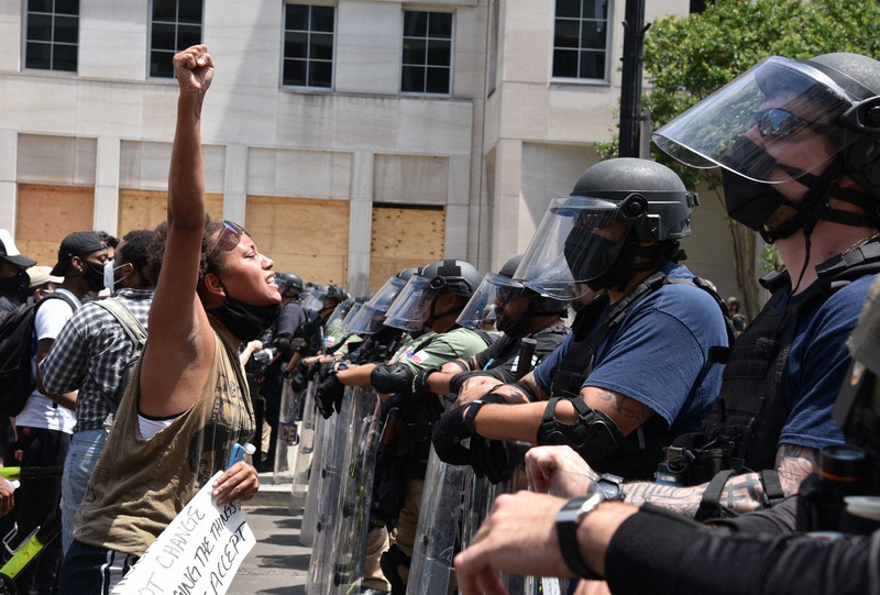 ホワイトハウス前で武装した警官隊に右拳を突き上げて抗議する黒人女性=首都ワシントンで2020年6月3日午後1時27分、鈴木一生撮影