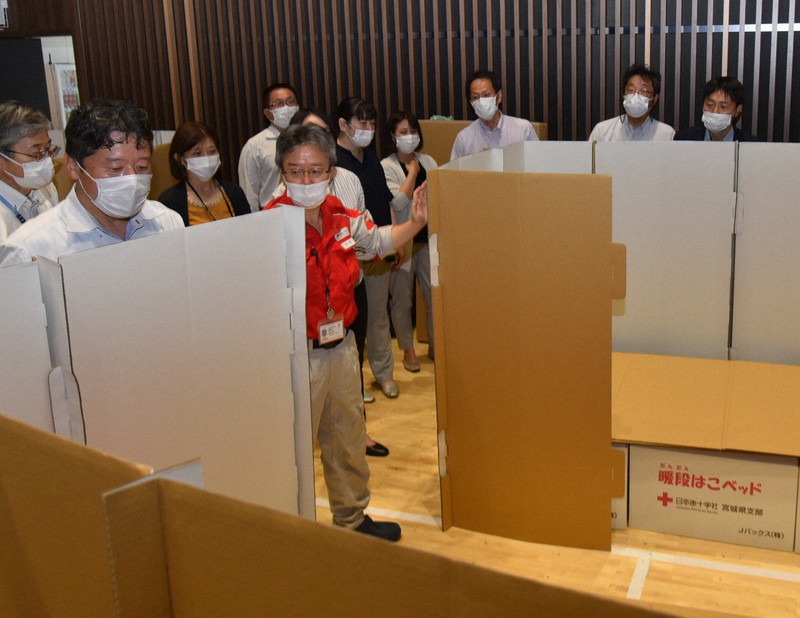 段ボール製のベッドと間仕切りの設営方法を実演する石巻赤十字病院の植田信策副院長(中央)=同病院で2020年6月24日、百武信幸撮影