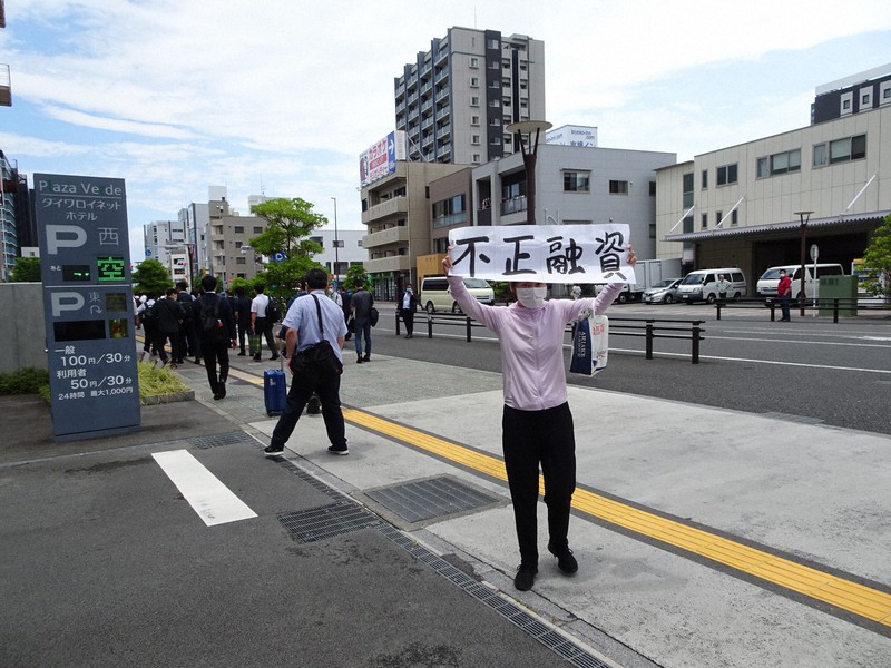 スルガ銀行の株主総会終了後、会場の外で「不正融資」の幕を掲げて抗議する出席株主の1人=静岡県沼津市で6月26日、今沢真撮影