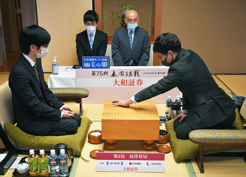 第75期本因坊決定戦七番勝負第4局で第1着を打つ本因坊文裕(右)。左は挑戦者の芝野虎丸名人。奥右は立会の武宮正樹九段=静岡県河津町の今井荘で2020年6月30日午前9時、手塚耕一郎撮影