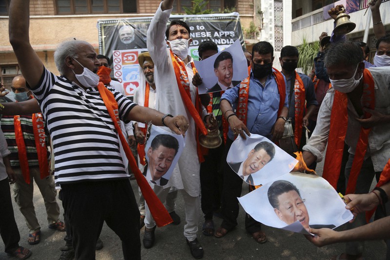 抗議のため中国の習近平国家主席の写真に火を付けるインドの活動家ら=北部ジャムで1日、AP