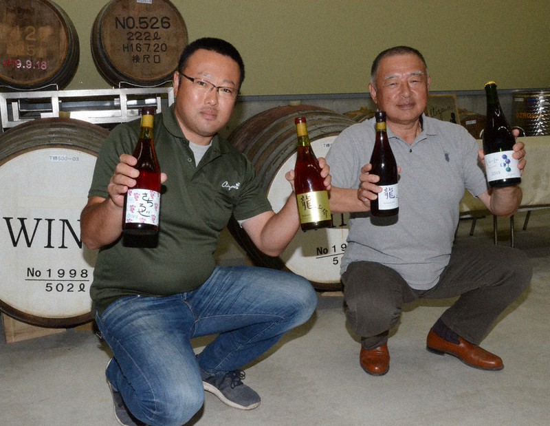 初仕込みのワインを手にする相沢一郎代表(左)と父で農場長の龍也さん=北海道帯広市で