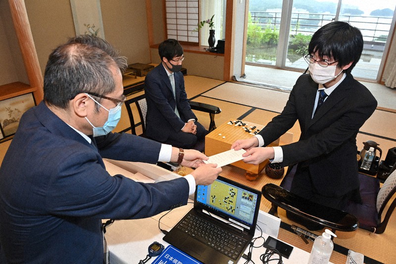 第75期本因坊決定戦七番勝負第5局の1日目を終え、封じ手を立会の山城宏九段(左)に渡す挑戦者の芝野虎丸名人(右)。中央は本因坊文裕=三重県鳥羽市の戸田家で8日午後5時6分、兵藤公治撮影