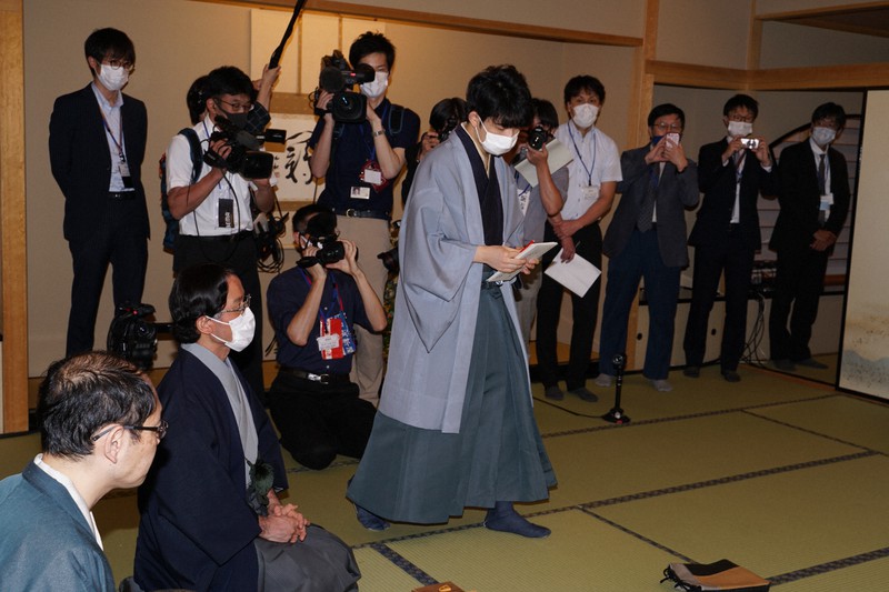 王位戦第2局1日目が終わり、封じ手を記入して対局室に戻る藤井聡太七段(中央)=日本将棋連盟提供