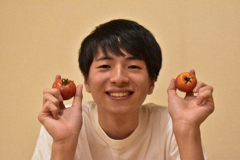 真っ赤なトマトを両手に、笑顔の工藤さん=本人提供