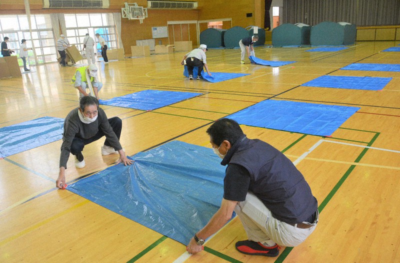 コロナ感染対策で間隔を空けて体育館にシートを敷く訓練参加者=秋田市の旭南小で