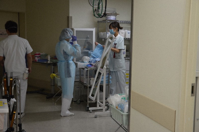 感染患者の病棟に入る前に防護服を着用し、確認する看護師=東京都江戸川区で4月