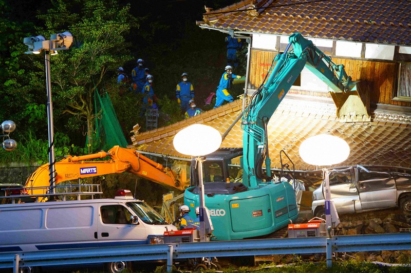 裏山が崩れて土砂が流入した住宅で、取り残された住人の捜索を続ける警察官ら=東広島市河内町宇山で2020年7月14日午後7時23分、中島昭浩撮影