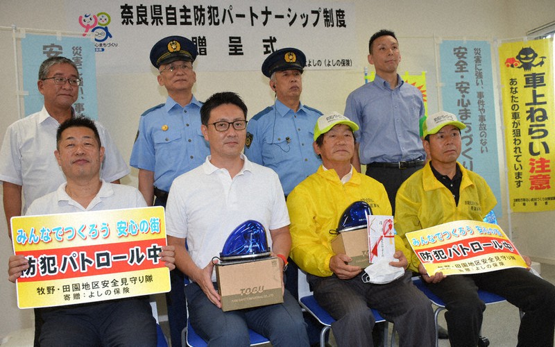 保険代理店「よしの保険」から自主防犯団体「牧野・田園地区安全見守り隊」に青色回転灯などが贈呈された=奈良県五條市田園2で、萱原健一撮影
