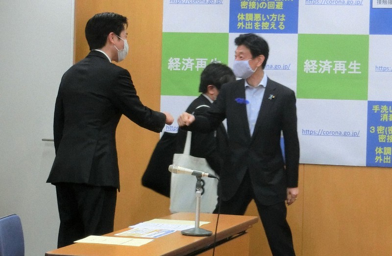 会談前、笑顔で「グータッチ」を交わす西村康稔経済再生担当相(右)と大阪府の吉村洋文知事=内閣府で7月15日午後1時15分、芝村侑美撮影