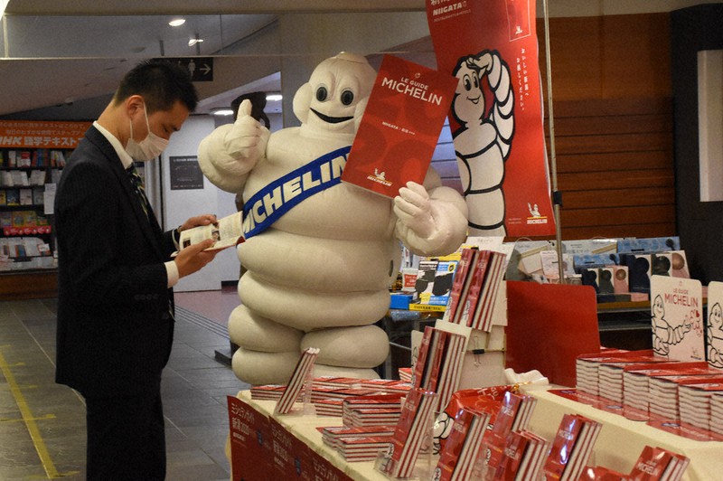 本を手にした男性にアピールするミシュランマン(C)MICHELIN=新潟市中央区の紀伊國屋書店新潟店で
