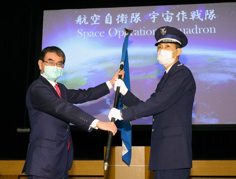 航空自衛隊「宇宙作戦隊」隊長の阿式俊英2等空佐(右)に隊旗を授与する河野太郎防衛相=東京都新宿区で2020年5月18日午後(代表撮影)