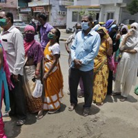 マスクを着用して列に並ぶ市民ら＝インド西部アーメダバードで2020年7月20日、AP