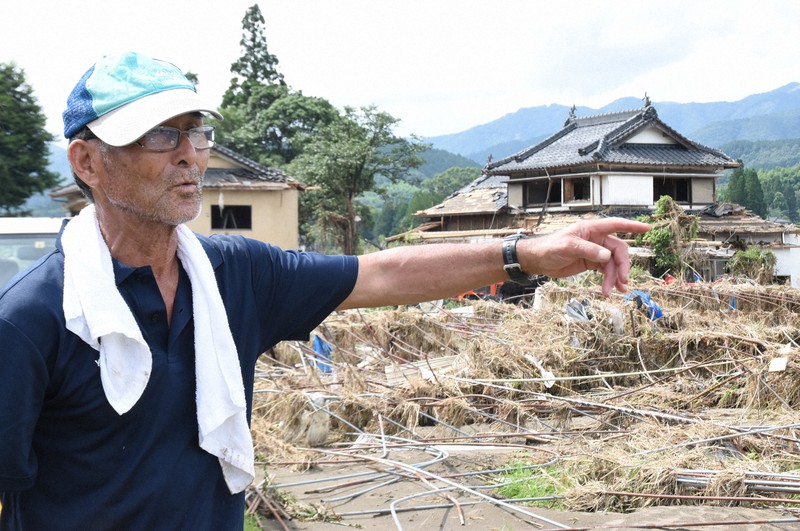 被災した自宅(右奥)近くから球磨川を見渡し、当時の状況を説明する一橋国広さん=熊本県人吉市中神町大柿地区で2020年7月12日午後3時12分、中山敦貴撮影
