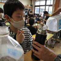 熱中症予防対策として備蓄していた水を地元漁協が寄せた氷で冷やし、水筒に入れてもらう児童＝福島県相馬市で2020年7月21日午後0時58分、和田大典撮影