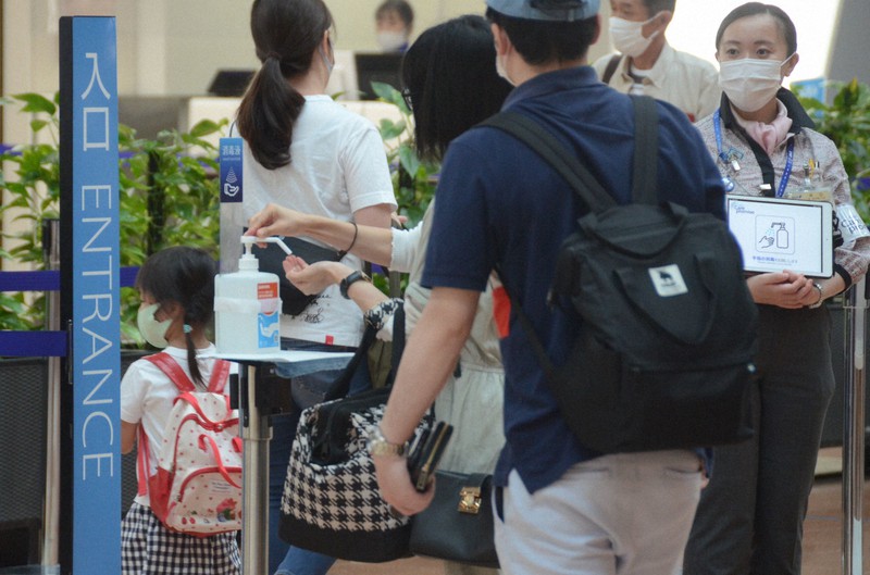 手指消毒をして保安検査場に向かう旅行者ら=東京都大田区の羽田空港で2020年7月22日午前11時29分、斎藤文太郎撮影