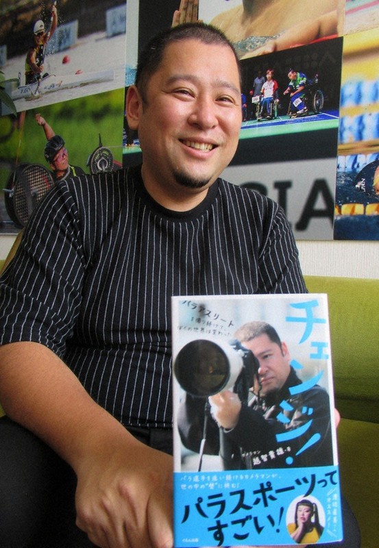 著書を手に「パラアスリートと出会って世界が広がった」と語るカメラマンの越智貴雄さん=東京都中央区で