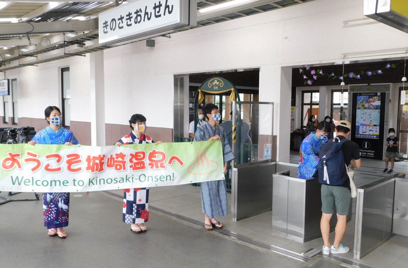 浴衣姿で「ようこそ城崎温泉へ」と書いた横断幕を掲げるJR城崎温泉駅員ら=兵庫県豊岡市城崎町今津で2020年7月23日午前9時57分、村瀬達男撮影