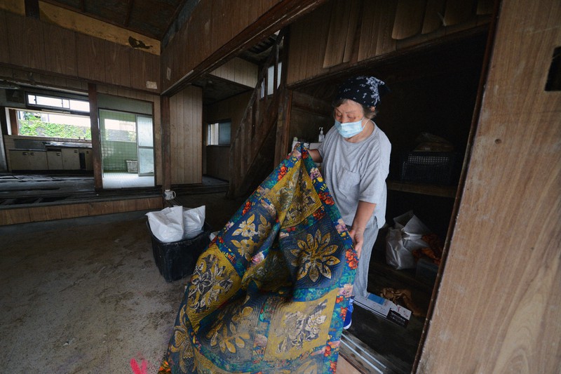 水につかった自宅兼店舗を片付ける江嶋信子さん。「まさか2階まで水がくるとは思わなかった」と振り返る=熊本県人吉市下青井町で2020年7月27日午前11時39分、菅野蘭撮影