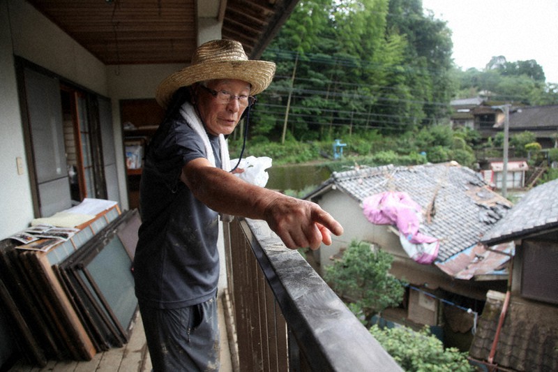 浸水した自宅2階のベランダに立ち、近所の男性を救助した状況を説明する浦野又生さん=7月12日