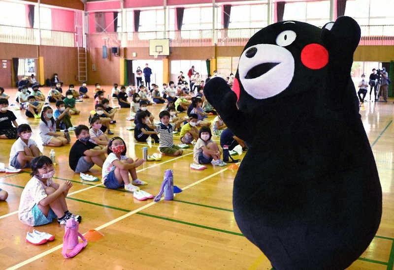 再開した学校に登校し、全校集会でくまモンに拍手をする児童たち