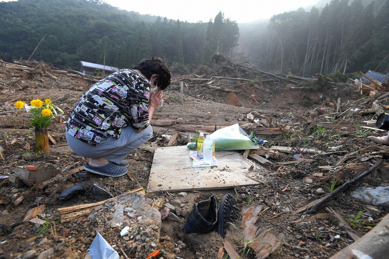 土砂崩れで住民3人が犠牲になった民家跡で手を合わせる近所の女性。「いい人たちでした」と故人を悼んだ=熊本県芦北町で2020年8月4日午前6時56分、津村豊和撮影