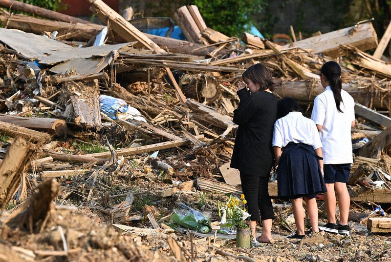 3人が犠牲になった熊本県芦北町の土砂崩れ現場では、亡くなった入江竜一さんの妻と娘2人が手を合わせた。他に亡くなったのは竜一さんの母と祖母。あの日、竜一さんは妻子と妻の実家に帰省中だったが、1人自宅に戻り巻き込まれた。妻は「母と祖母が心配だったんだろう。優しい人でした」と涙ぐんだ=4日午後5時32分、徳野仁子撮影