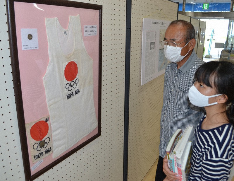 有田町東図書館で56年前の聖火リレーのユニホームを見つめる来場者