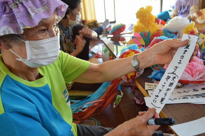 亡くなった矢野まさ子さんへの思いを短冊にしたためた女性=熊本県芦北町伏木氏で2020年8月6日午前9時半、浅野翔太郎撮影