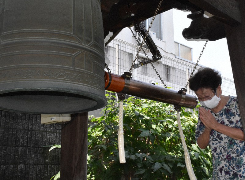 鐘を突く前に手を合わせ、祈りをささげる参列者=京都市上京区の本久寺で、中島怜子撮影