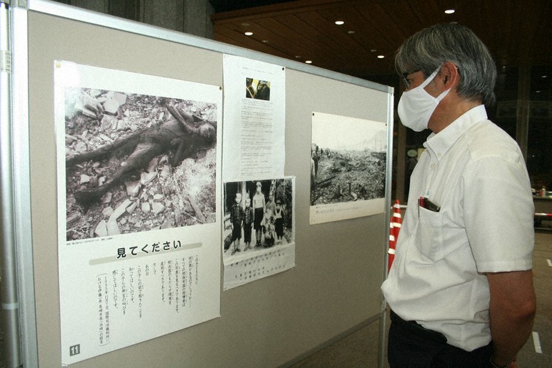 原爆で亡くなった少年の写真を見つめる熊本被爆二世・三世の会の青木栄会長