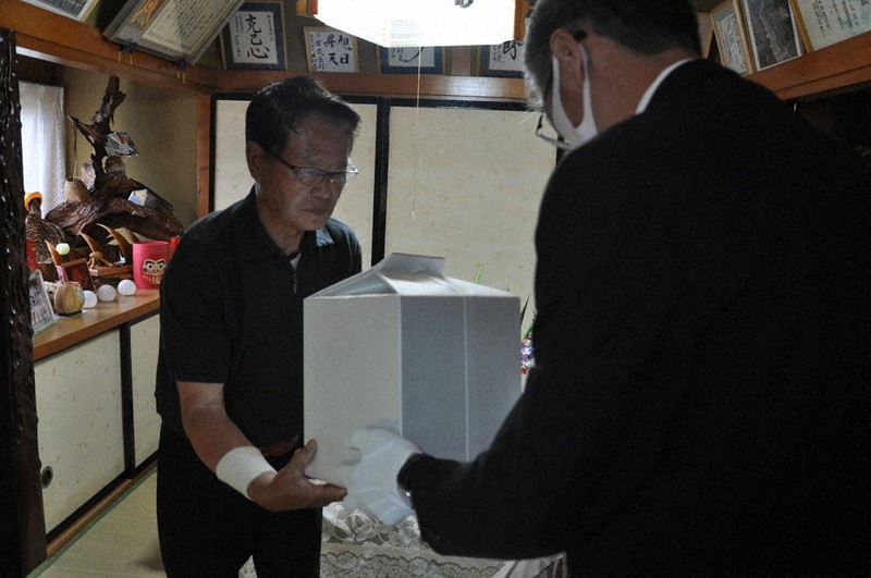 青森県の担当者(右)から遺骨を受け取る岩泉盛利さん=青森県大間町奥戸で2020年8月6日、野呂賢治撮影