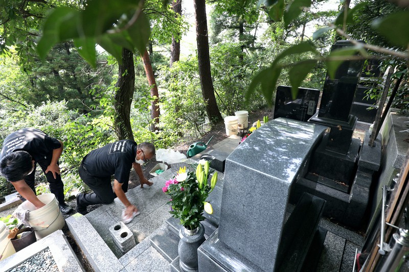 墓の土台まで丁寧に拭き掃除する地元の業者=福島市で2020年8月5日、小川昌宏撮影