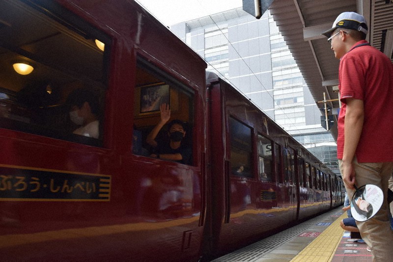 JR博多駅のホームを出発する「いさぶろう・しんぺい」と「かわせみ やませみ」の臨時列車から手を振る乗客(中央)