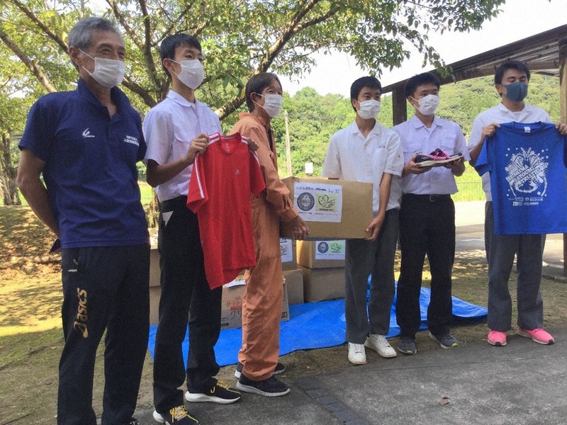 寄贈されたシューズやウェアを手にする人吉市陸協のメンバーら