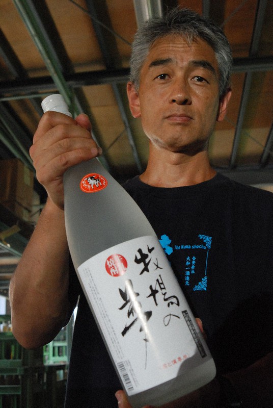 洗浄作業が終わった一升瓶を手に「応援してもらいありがたい」と話す「大和一酒造元」の下田代表